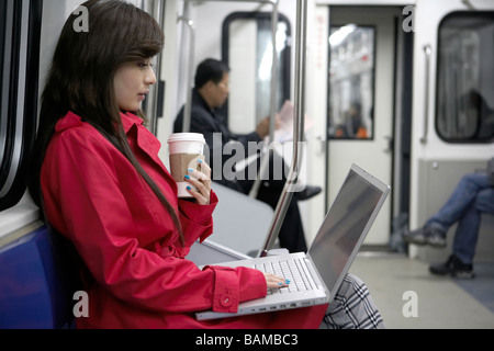 Woman Sitting On Train Typing On Laptop Stock Photo