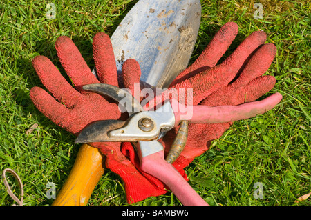Gardening garden tools Gloves Hand Trowel and Pruning Secateurs Laying On The Grass Stock Photo