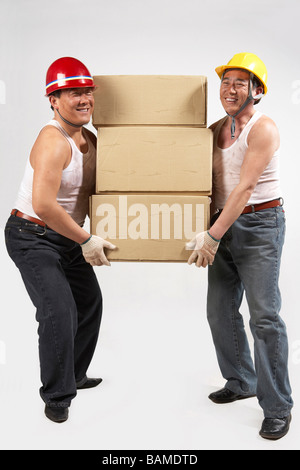 Men Wearing Hard Hats Lifting A Large Box Stock Photo