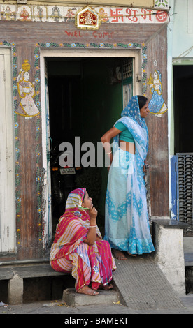 Women in brightly coloured saris standing in a decorated doorway in Udaipur, India Stock Photo