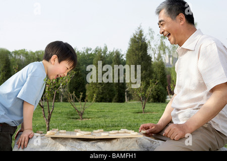 Grandfather And Grandson Playing A Boardgame In The Park Stock Photo