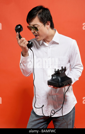 Young Man Yelling At Telephone Stock Photo