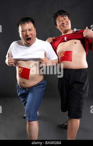 Portrait Of Fans With Flags Painted On Their Stomachs Stock Photo