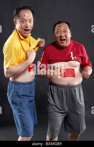 Portrait Of Fans With Flags Painted On Their Stomachs Stock Photo