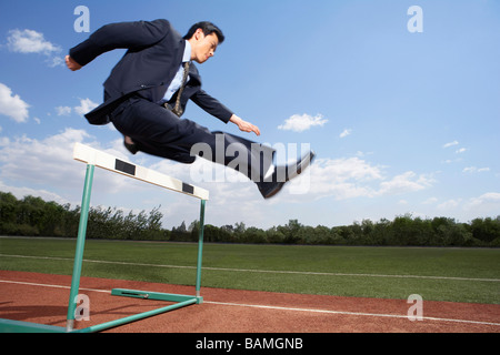 Businessman In His Suit Jumping A Hurdle Stock Photo