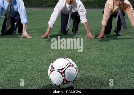 Businessmen On A Field Preparing To Run To A Soccer Ball Stock Photo