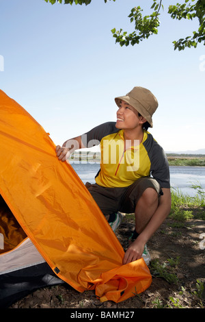 Young Man Setting Up A Tent While Camping Stock Photo