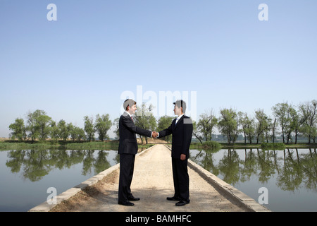 Businessmen Standing Next To A Lake On A Bridge Stock Photo