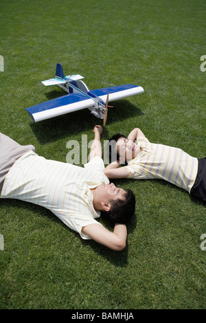 Father And Son Laying Down After Playing With Model Airplane Stock Photo
