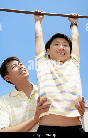 Father Helping Son Hang From Bar Stock Photo