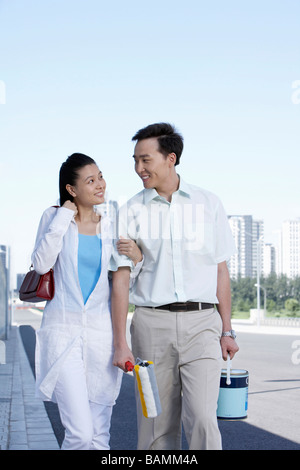 Man And Woman Linking Arms, Walking And Smiling At Each Other Stock Photo