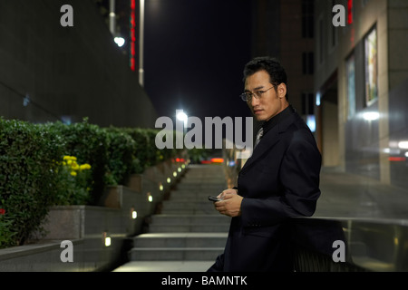Businessman Leaning On Stair-Rail And Using Cellphone Stock Photo