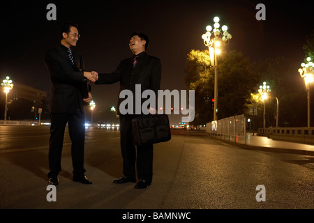 Two Businessmen Shaking Hands Outside At Night Stock Photo