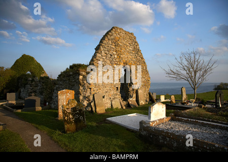 Historic 16th century ruins of St Dwynwen's church with Celtic cross on