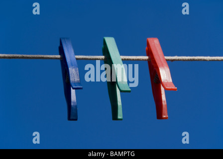 Red green and blue plastic clothes pegs on a washing line Stock Photo