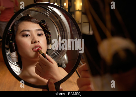 Woman Looking In The Mirror Applying Lipstick Stock Photo