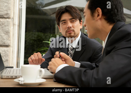 Two Businessmen Using Laptop At Cafe Stock Photo