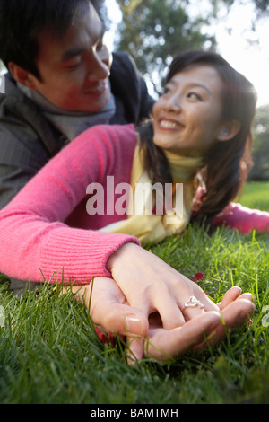 Couple Rolling On Grass, Holding Hands Stock Photo