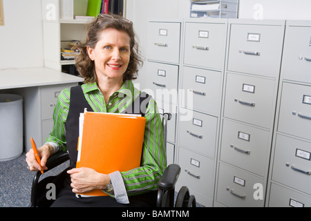 Woman in wheelchair holding files Stock Photo