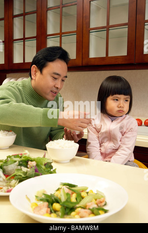 Man trying to feed his daughter Stock Photo