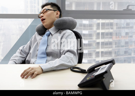 Businessman In Office Resting With Neck Pillow Stock Photo