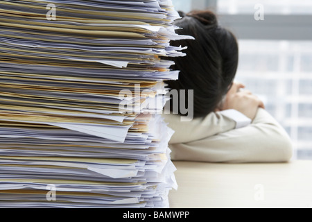 Businesswoman Sleeping Next To Pile Of Work Stock Photo