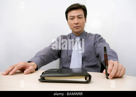 Businessman Sitting At Conference Table, Frowning Stock Photo