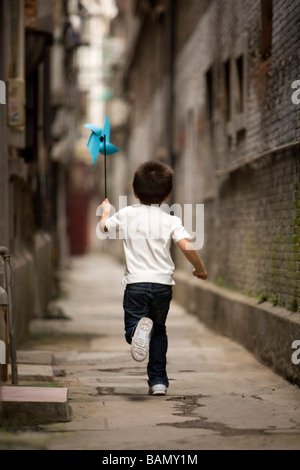 A child runs with a paper pinwheel Stock Photo