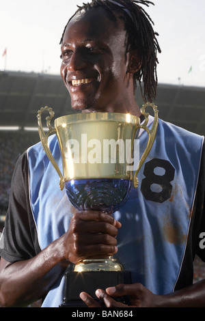Male soccer player proudly holding trophy