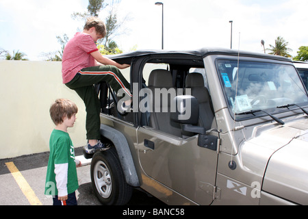 child climbing into a locked car, jeep Stock Photo