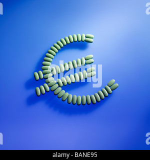 green pills laid out in the Euro money sign symbol on blue background Stock Photo