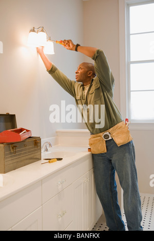 African man repairing light fixture Stock Photo