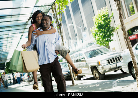 African man giving girlfriend piggyback ride Stock Photo