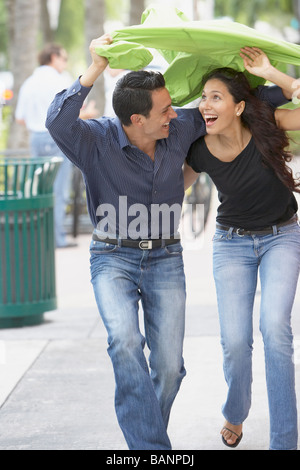 Couple holding raincoat over heads Stock Photo