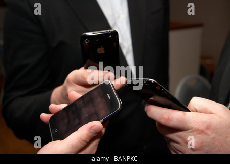 three businessmen look at their iphones Stock Photo
