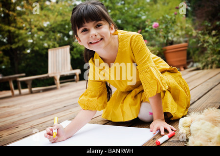 Mixed race girl coloring on deck Stock Photo