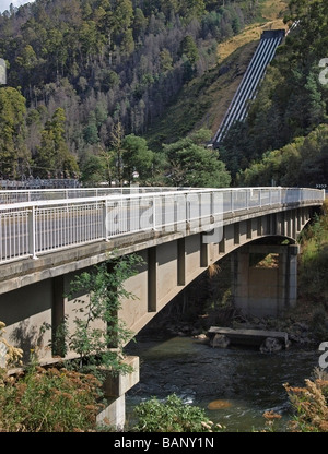 BRIDGE OVER A RIVER WITH  PART OF THE HYDROELECTRIC SCHEME AT TUNGATINAH ON HILLSIDE BEHIND TASMANIA AUSTRALIA Stock Photo