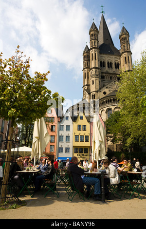 people enjoying warm weather at Biergarten, Cologne Old Town, church Saint Martin in background Stock Photo