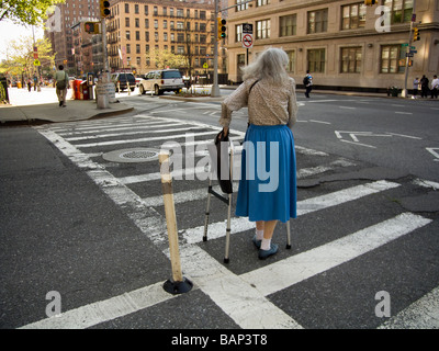 Elderly woman with walker crossing street at zebra crossing in city ...
