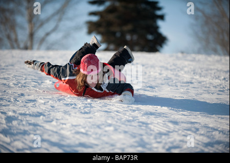 Girl sledding down the tobogganing hill Stock Photo