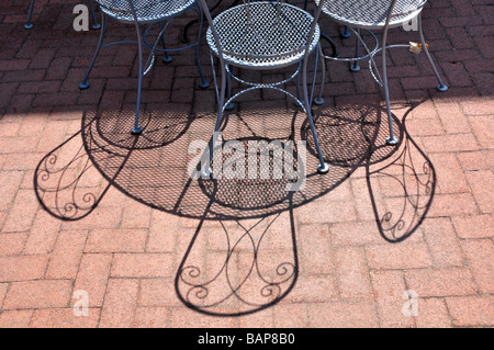 Interesting shadows formed by metal chairson red brick. Stock Photo