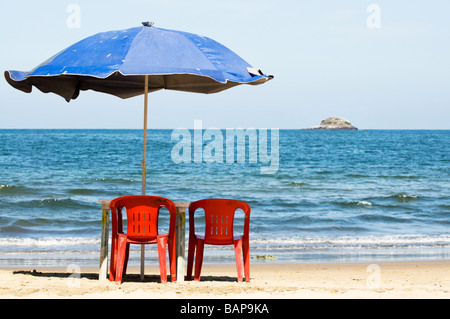 Two empty chairs and an umbrella sit unused on a sandy beach in Mexico. Stock Photo