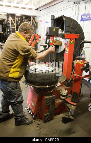 man fitting new tyre on wheel Stock Photo