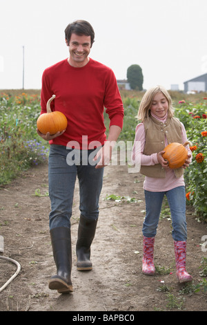 Father and daughter with organic pumpkins walking in farm fields, Ladner, British Columbia Stock Photo