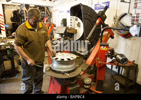 man fitting new tyre on wheel Stock Photo