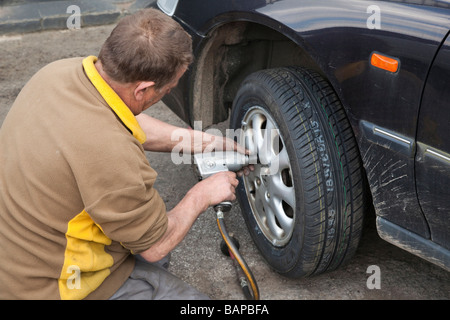 man fitting new tyre on car Stock Photo