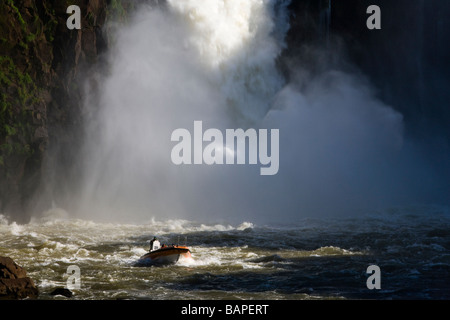 Exciting adventure tourist activity boat ride takes tourists in heavy mist of San Martin Falls at Iguazu Falls Argentina UNESCO World Heritage site Stock Photo