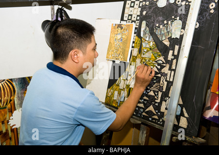 Artist painting intricate detail into Vietnamese Lacquerware copy of a Gustav Klimt Painting. Ho Chi Minh City, Vietnam. Stock Photo