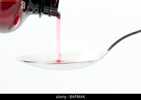 Cough syrup pooring from the container into a metal spoon on white bachground Stock Photo