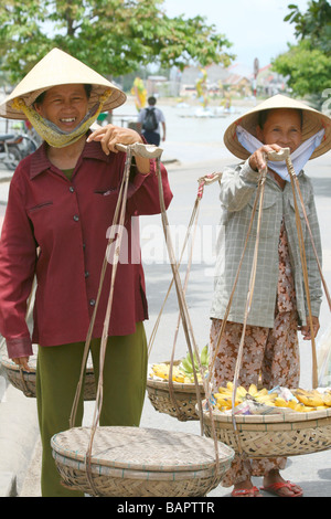 Two female street vendors selling their wares in traditional Vietnamese style in Hoi An, Vietnam